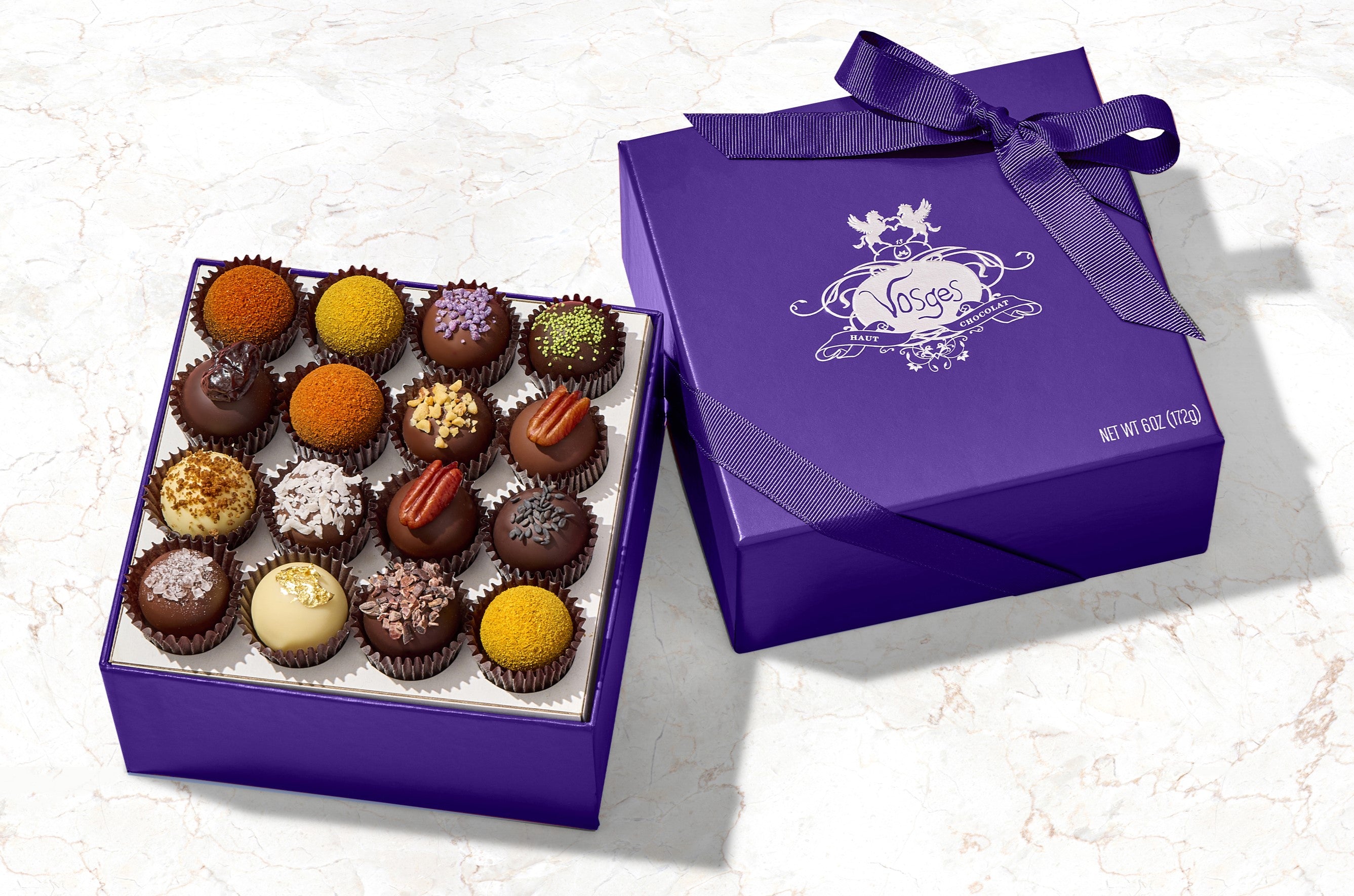 A purple gift box of Vosges exotic 16- piece truffle collection on a marble background