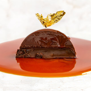 A Vosges La Bombe in a pool of dulce de leche topped with an edible gold leaf