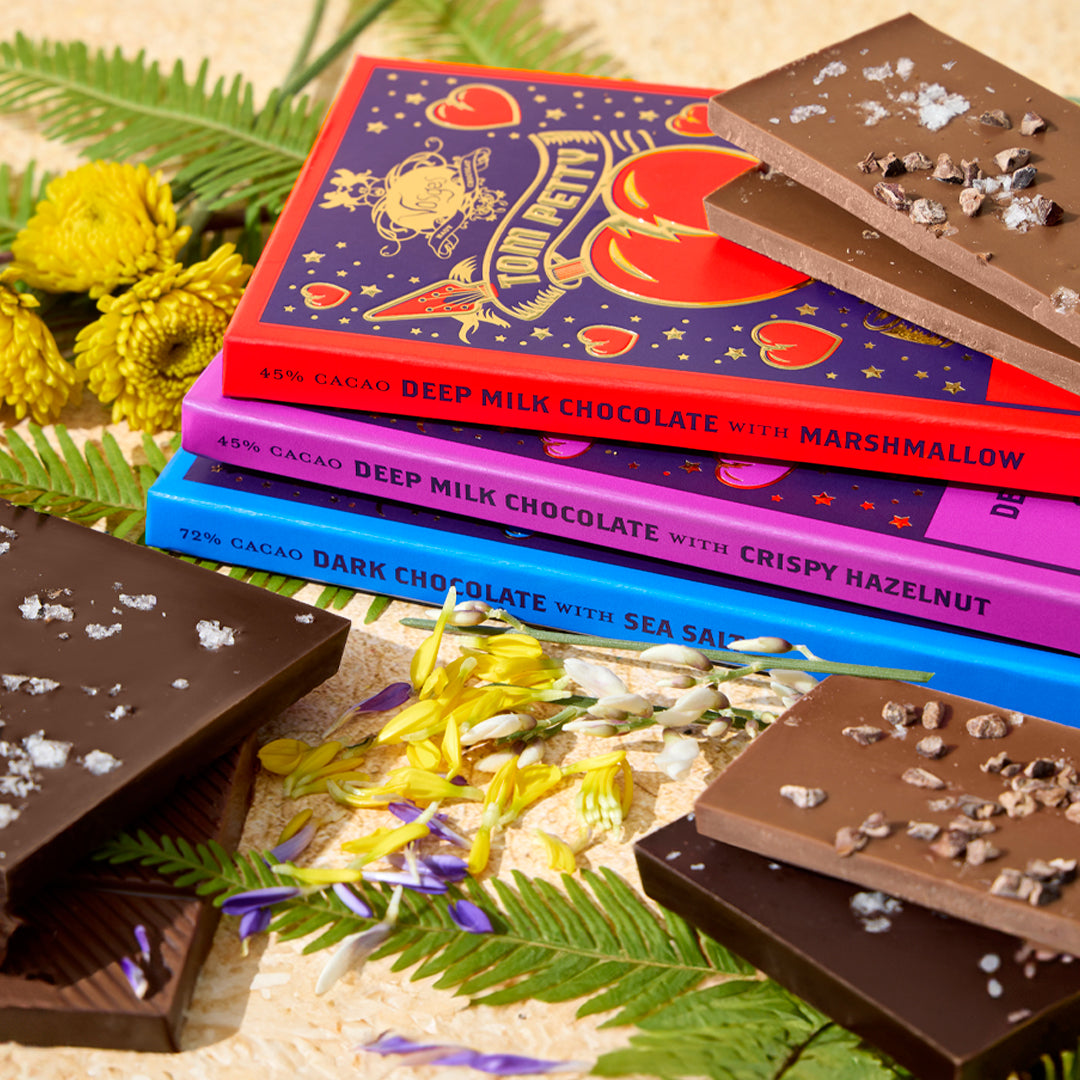 Three wrapped Tom Petty x Vosges Haut-Chocolat Collection bars with flowers and various chocolate bars 