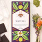 Vosges Matcha Green Tea Spirulina chocolate bar beside a bundle of dried flowers, green matcha powder, and several crystals on a white background.