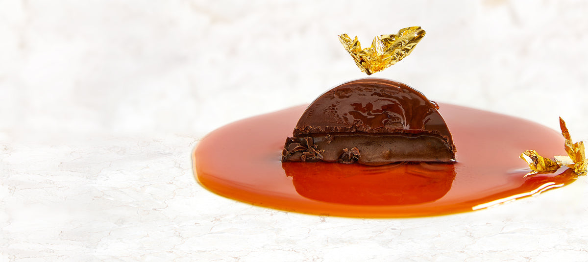 A Vosges La Bombe in a pool of dulce de leche topped with an edible gold leaf